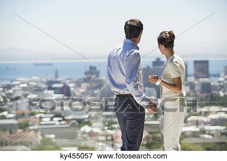 Couple looking at city view from a terrace View Large Photo Image Stock Photo - Couple looking at city view from a terrace. Fotosearch