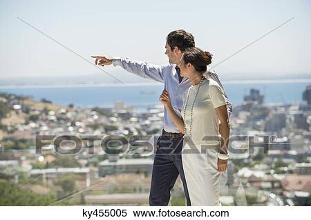 Couple looking at city view from a terrace View Large Photo Image Stock Photography - Couple looking at city view from a terrace. Fotosearch