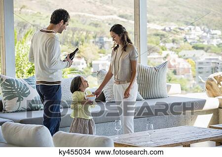Picture - Couple standing in a living room with their daughter. Fotosearch