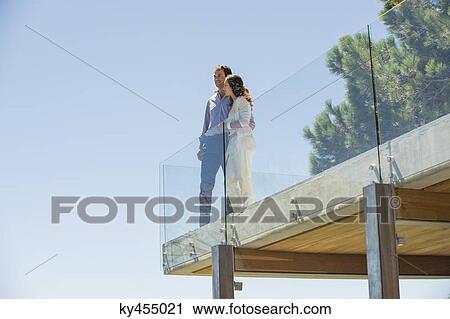 Couple standing together on a terrace View Large Photo Image Stock Image - Couple standing together on a terrace. Fotosearch