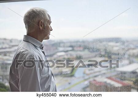 Stock Image - Man looking through a window. Fotosearch
