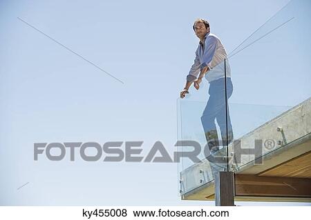 Man standing on the terrace looking away View Large Photo Image Stock Photo - Man standing on the terrace looking away. Fotosearch