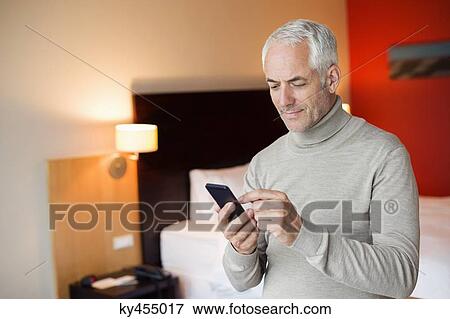 Man using a cell phone in a hotel room View Large Photo Image Stock Photo - Man using a cell phone in a hotel room. Fotosearch