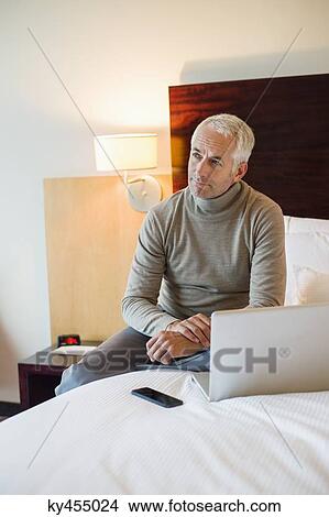 Man using a laptop in a hotel room View Large Photo Image Picture - Man using a laptop in a hotel room. Fotosearch