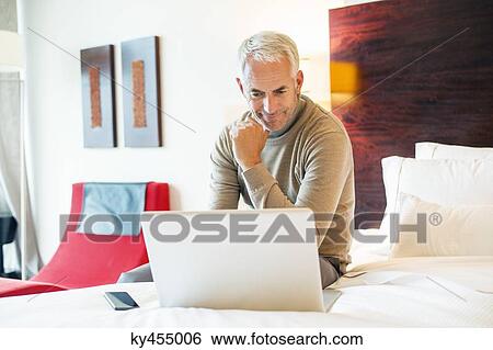 Man using a laptop in a hotel room View Large Photo Image Stock Photograph - Man using a laptop in a hotel room. Fotosearch