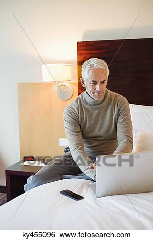 Man using a laptop in a hotel room View Large Photo Image Stock Photograph - Man using a laptop in a hotel room. Fotosearch