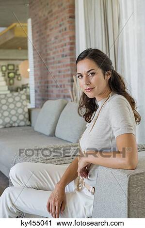 Portrait of a beautiful woman sitting on a couch View Large Photo Image Stock Image - Portrait of a beautiful woman sitting on a couch. Fotosearch