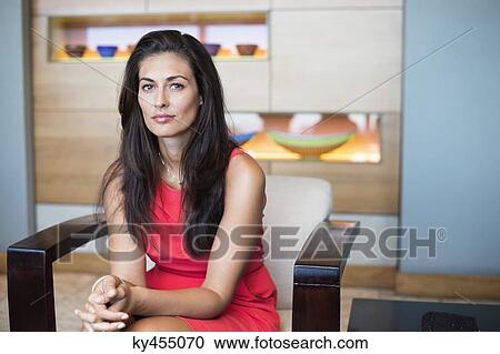 Stock Image - Portrait of a beautiful woman sitting on a chair. Fotosearch