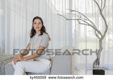 Portrait of a beautiful woman sitting on a couch View Large Photo Image Stock Photo - Portrait of a beautiful woman sitting on a couch. Fotosearch