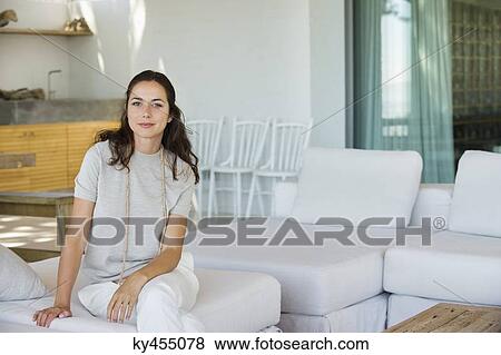 Portrait of a beautiful woman sitting on a couch View Large Photo Image Stock Photo - Portrait of a beautiful woman sitting on a couch. Fotosearch