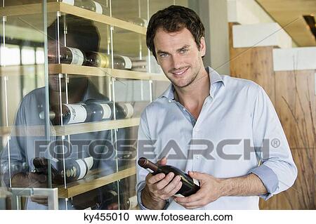 Portrait of a smiling man holding a wine bottle View Large Photo Image Stock Image - Portrait of a smiling man holding a wine bottle. Fotosearch
