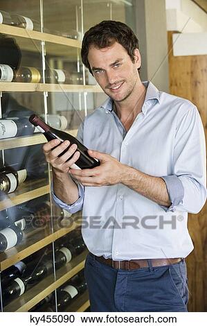 Portrait of a smiling man holding a wine bottle View Large Photo Image Stock Image - Portrait of a smiling man holding a wine bottle. Fotosearch
