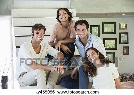 Stock Photograph - Portrait of smiling friends sitting on steps. Fotosearch
