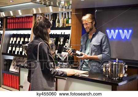 Sales clerk giving a wine bottle to a customer View Large Photo Image Stock Image - Sales clerk giving a wine bottle to a customer. Fotosearch