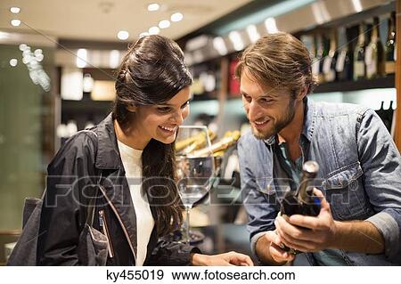 Sales clerk showing a wine bottle to a customer View Large Photo Image Stock Photo - Sales clerk showing a wine bottle to a customer. Fotosearch