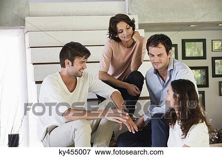 Stock Photo - Smiling friends sitting on steps talking to each other. Fotosearch