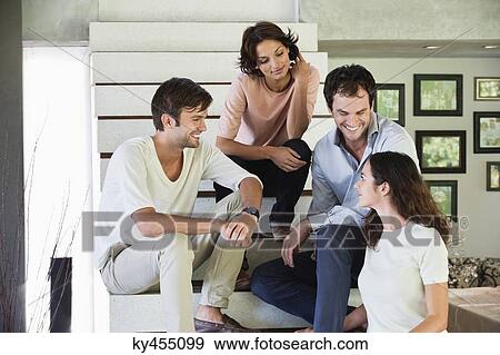 Smiling friends sitting on steps talking to each other View Large Photo Image Stock Photo - Smiling friends sitting on steps talking to each other. Fotosearch