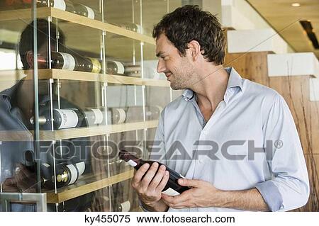 Smiling man holding a wine bottle View Large Photo Image Stock Photography - Smiling man holding a wine bottle. Fotosearch