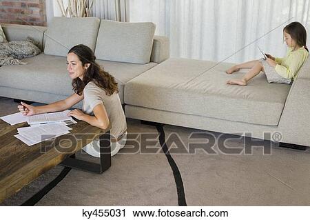 Woman doing paperwork with her daughter using a digital tablet at home View Large Photo Image Stock Image - Woman doing paperwork with her daughter using a digital tablet at home. Fotosearch