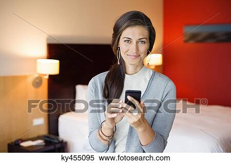 Woman using a cell phone in a hotel room View Large Photo Image Stock Photography - Woman using a cell phone in a hotel room. Fotosearch