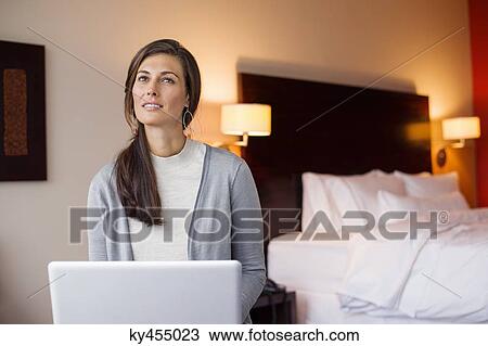 Stock Image - Woman using a laptop in a hotel room. Fotosearch
