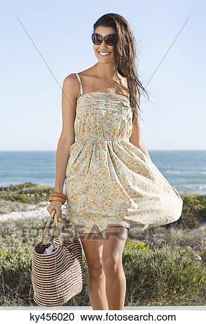 Stock Image - Beautiful woman carrying a bag on the beach. Fotosearch