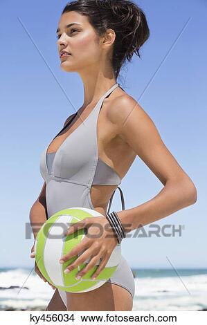Picture - Beautiful woman holding a volleyball on the beach. Fotosearch