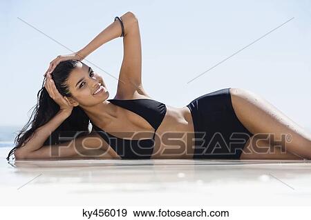 Stock Photo - Beautiful woman in bikini lying on the beach. Fotosearch
