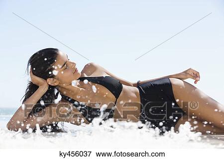 Stock Photo - Beautiful woman in bikini lying on the beach. Fotosearch