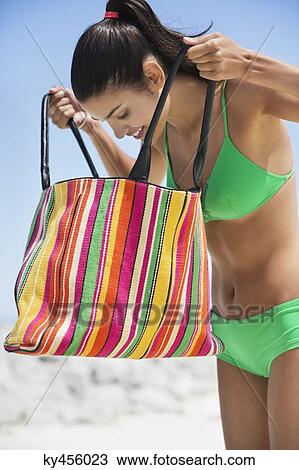 Beautiful woman looking into her bag on the beach View Large Photo Image Stock Image - Beautiful woman looking into her bag on the beach. Fotosearch