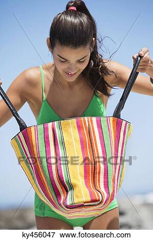 Beautiful woman looking into her bag on the beach View Large Photo Image Stock Photo - Beautiful woman looking into her bag on the beach. Fotosearch
