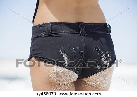 Stock Image - Rear view of a woman standing on the beach. Fotosearch