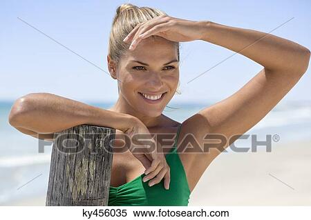 Smiling woman leaning against a wooden post on the beach View Large Photo Image Stock Photography - Smiling woman leaning against a wooden post on the beach. Fotosearch