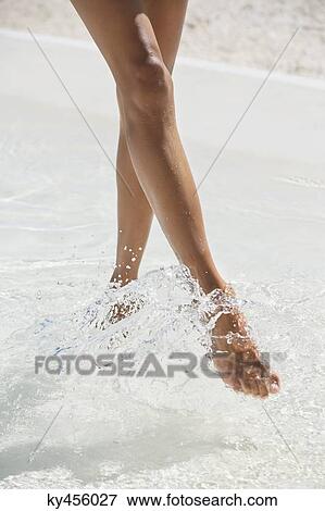 Woman splashing water with her feet on the beach View Large Photo Image Stock Photo - Woman splashing water with her feet on the beach. Fotosearch