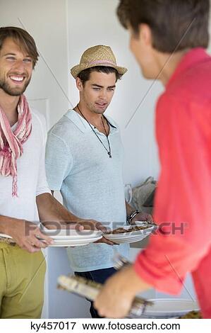 Friends arranging plates on a dining table View Large Photo Image Stock Photo - Friends arranging plates on a dining table. Fotosearch