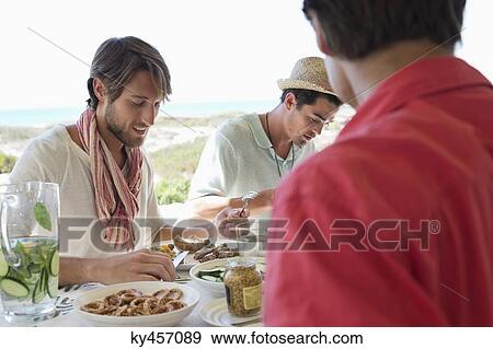 Friends eating lunch at dining table View Large Photo Image Stock Photo - Friends eating lunch at dining table. Fotosearch