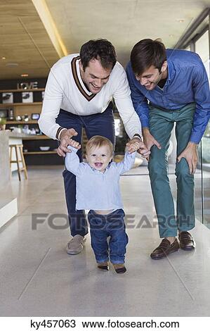 Stock Image - Parents helping their son to walk. Fotosearch