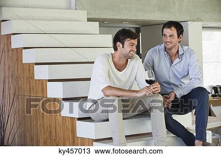 Smiling male friends sitting on steps with red wine View Large Photo Image Stock Image - Smiling male friends sitting on steps with red wine. Fotosearch