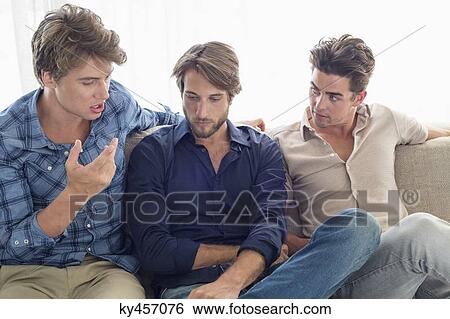 Three friends sitting on couch talking together View Large Photo Image Stock Photograph - Three friends sitting on couch talking together. Fotosearch