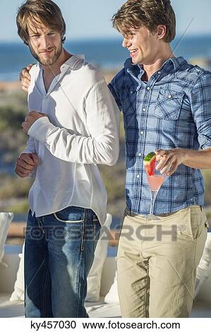 Stock Image - Two male friends enjoying drink in outdoor. Fotosearch