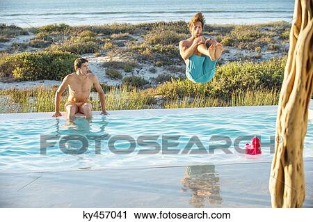 Two male friends enjoying in a swimming pool on the beach View Large Photo Image Stock Image - Two male friends enjoying in a swimming pool on the beach. Fotosearch