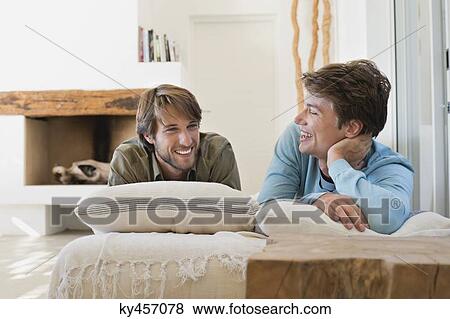 Stock Photo - Two male friends smiling on the bed. Fotosearch