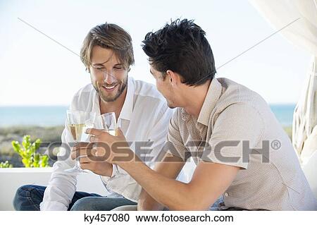 Two male friends toasting with wine View Large Photo Image Stock Image - Two male friends toasting with wine. Fotosearch