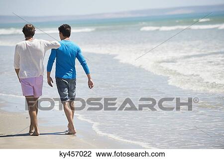 Stock Image - Two men walking on the beach. Fotosearch