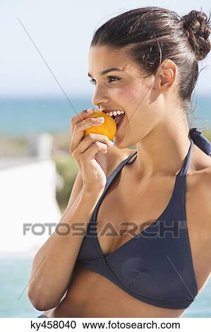 Beautiful woman eating a tomato on the beach View Large Photo Image Stock Image - Beautiful woman eating a tomato on the beach. Fotosearch