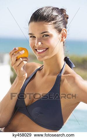Beautiful woman eating a tomato on the beach View Large Photo Image Stock Photo - Beautiful woman eating a tomato on the beach. Fotosearch