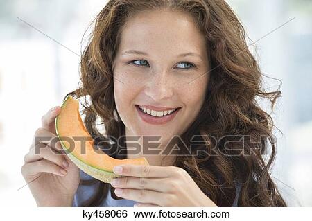 Close-up of a smiling woman eating melon View Large Photo Image Stock Photograph - Close-up of a smiling woman eating melon. Fotosearch