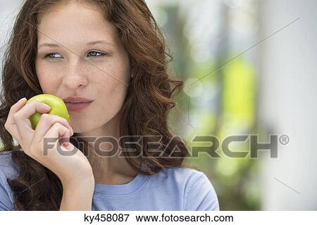 Stock Photo - Close-up of a woman eating a green apple. Fotosearch