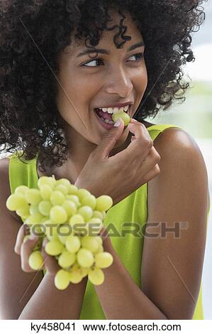 Stock Image - Close-up of a woman eating grapes. Fotosearch