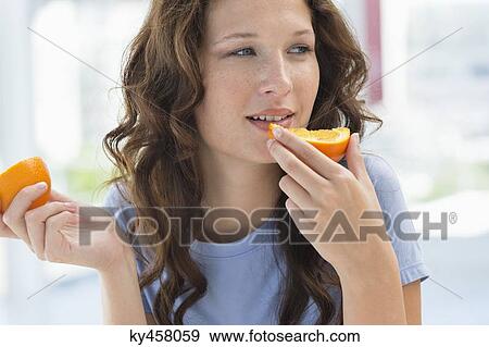 Stock Photo - Close-up of a woman eating orange. Fotosearch